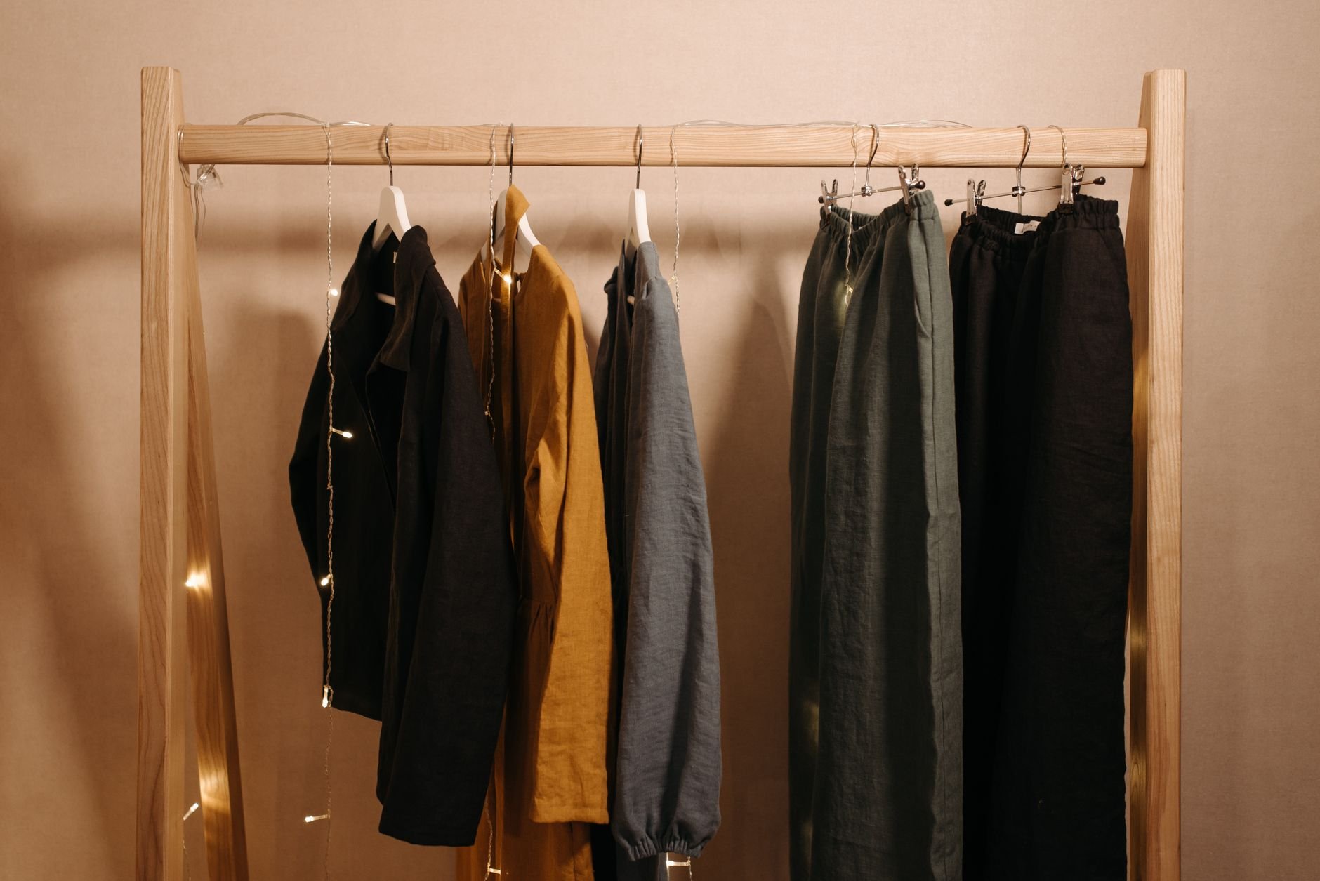 Natural fabric clothes hanging on a wooden rack — curated boutique wardrobe
